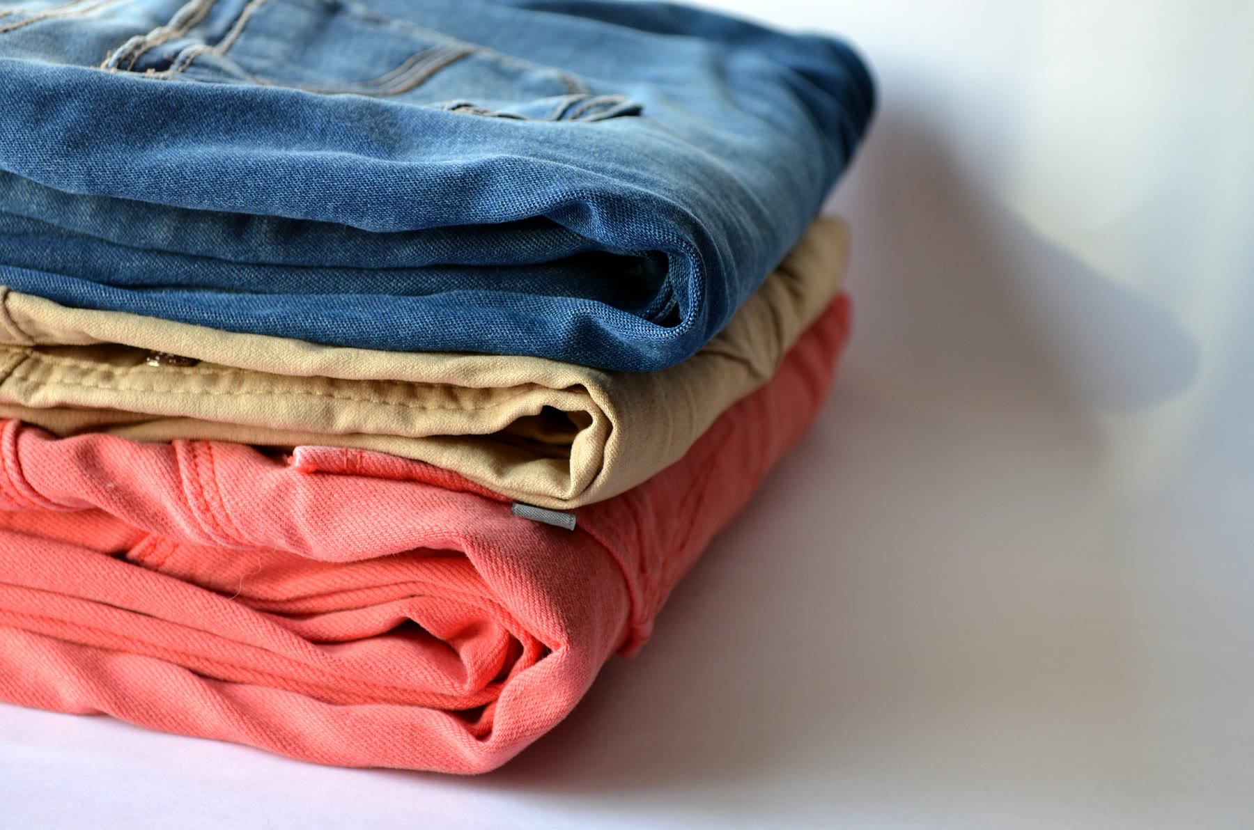 Gestapelde jeans en broeken in denim, camel en koraal