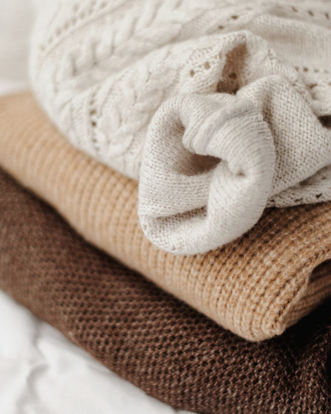 Stapel zachte gebreide truien in creme, camel en bruin