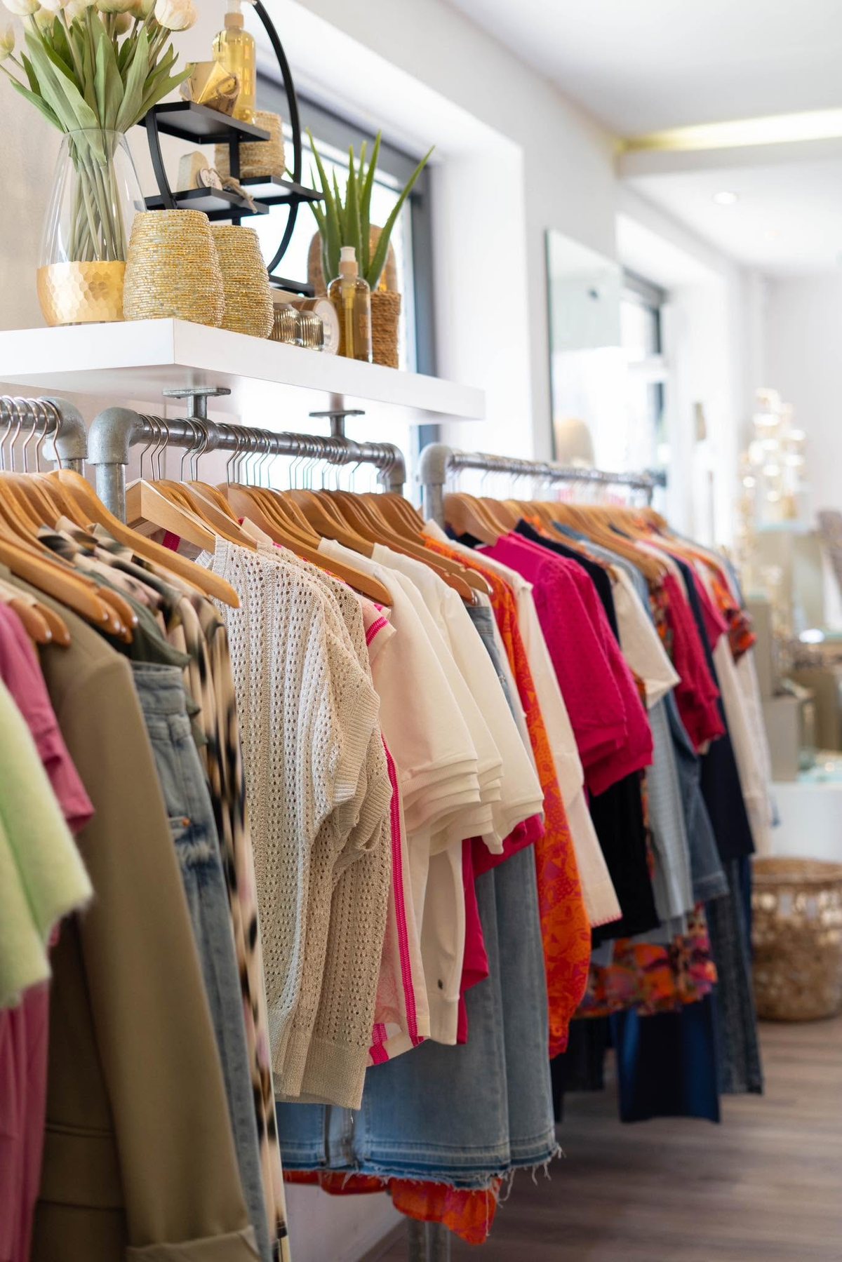 Lichte winkel met rekken vol kleding en planten in de vensterbank