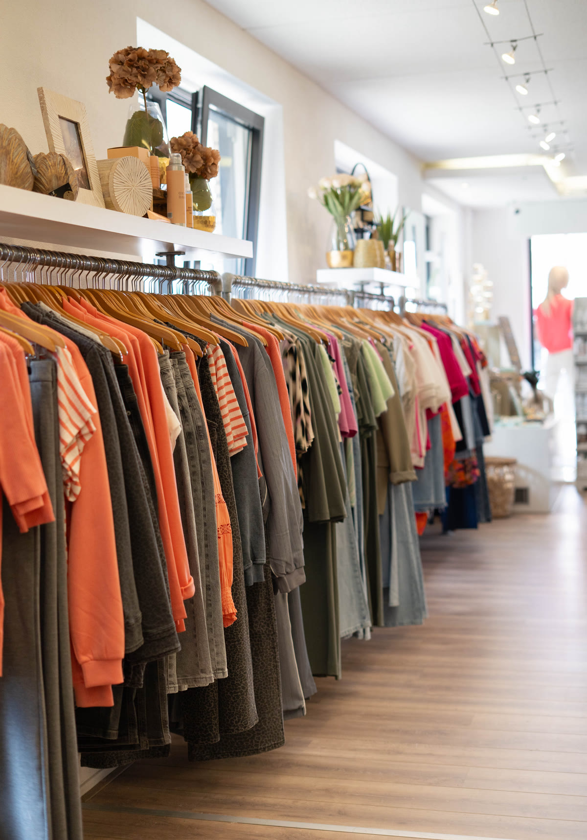 Rekken vol kleurrijke kleding in terracotta, olijf en roze